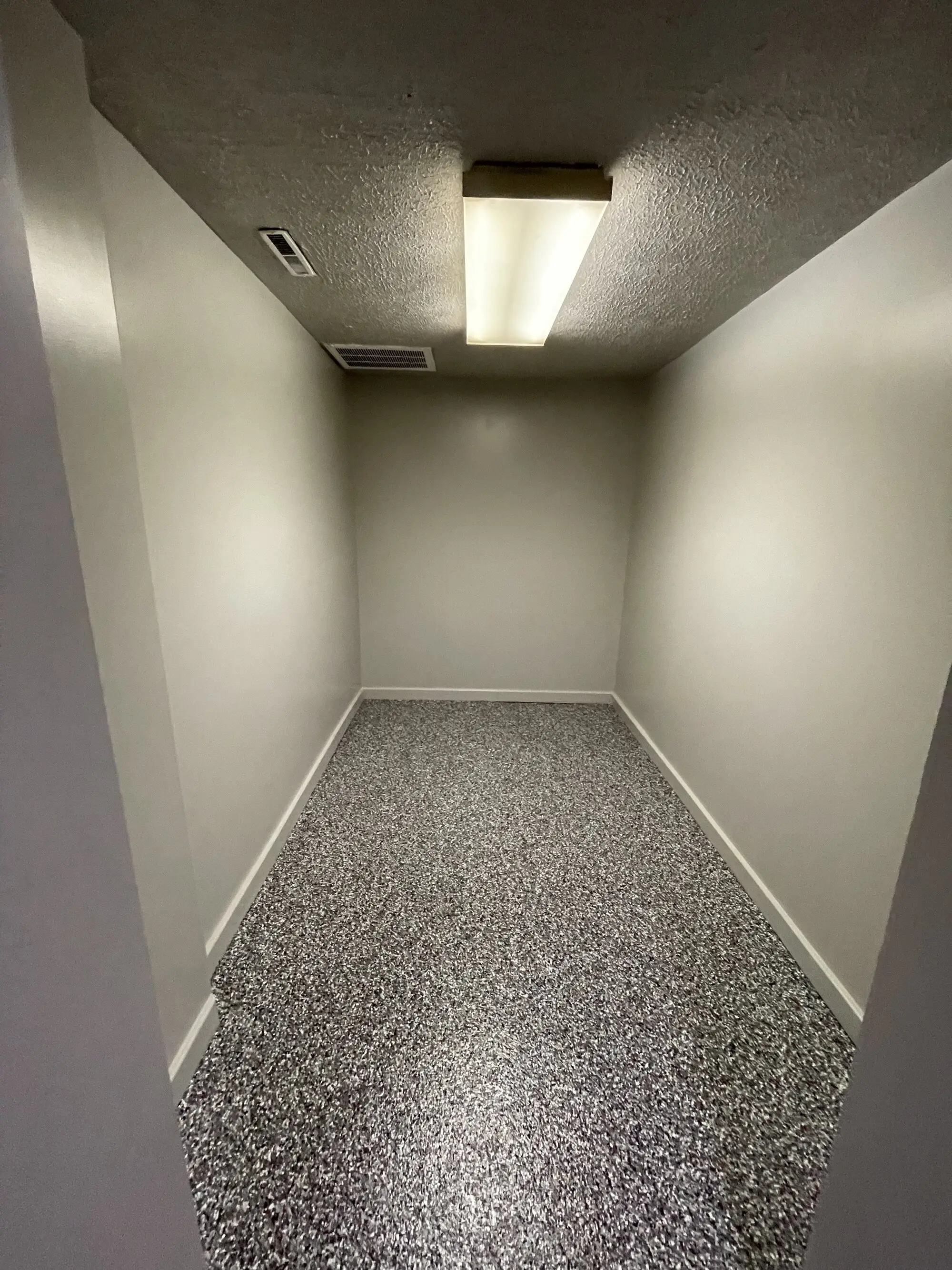 The same back room with light grey walls, a white baseboard and a grey flake floor coating