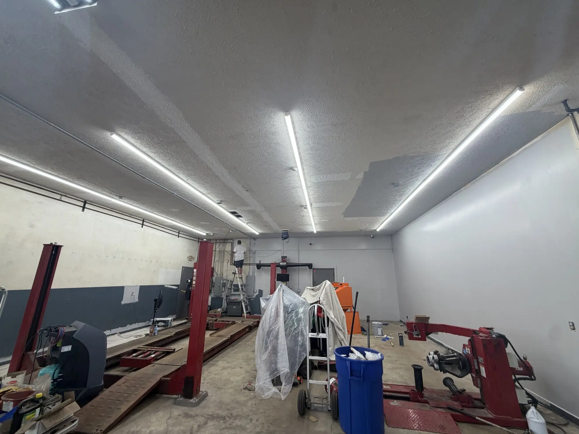 Auto shop bay before painting, stained walls and ceiling with equipment sheeted over