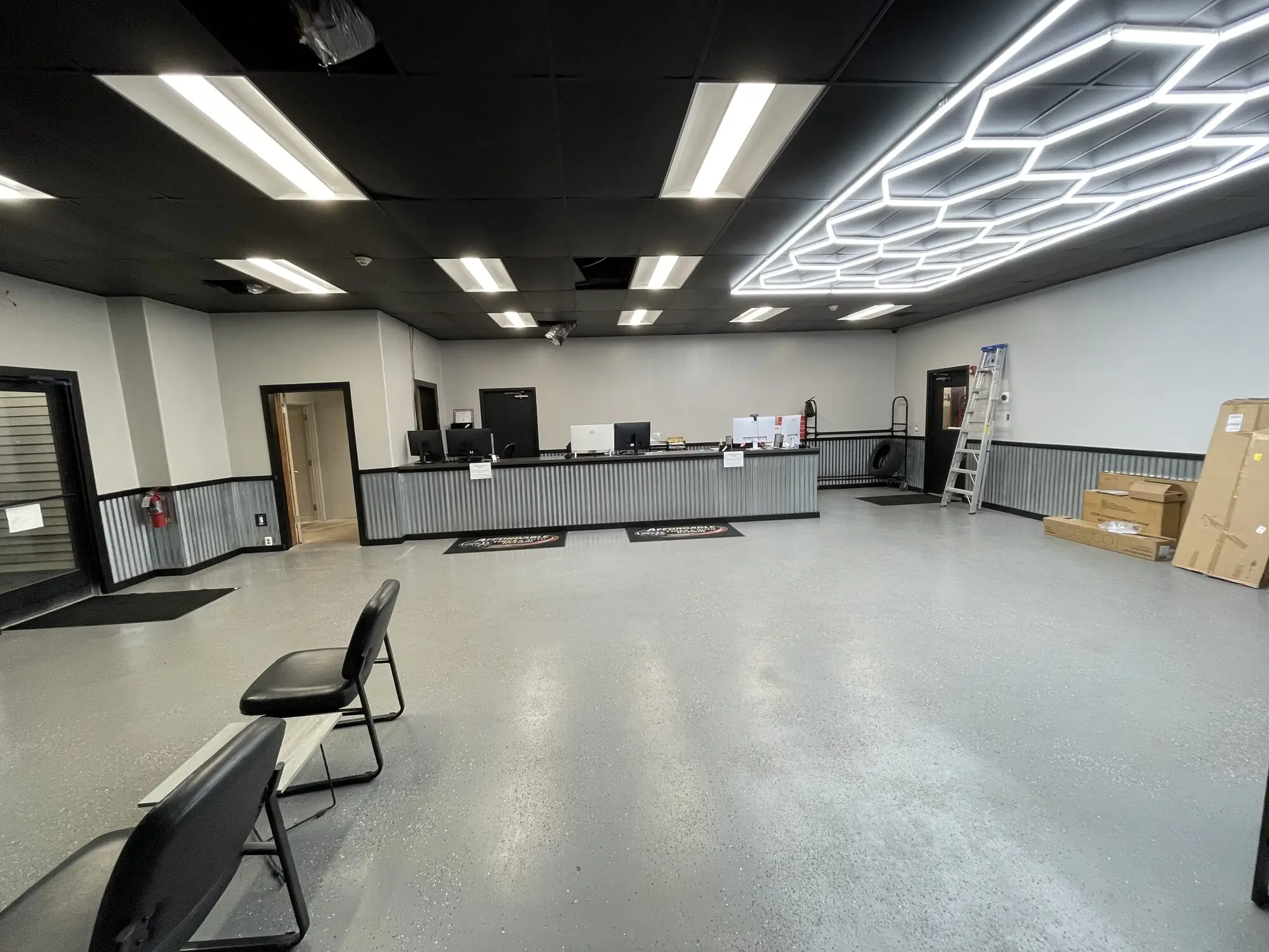 Commercial showroom with white walls, a dark ceiling grid and a corrugated metal wainscot