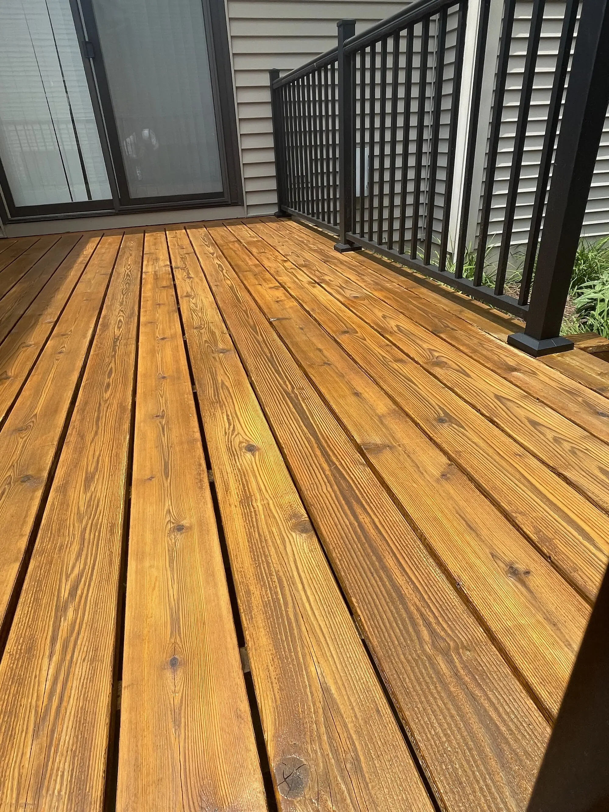 Freshly stained cedar deck boards running to a black rail and sliding doors