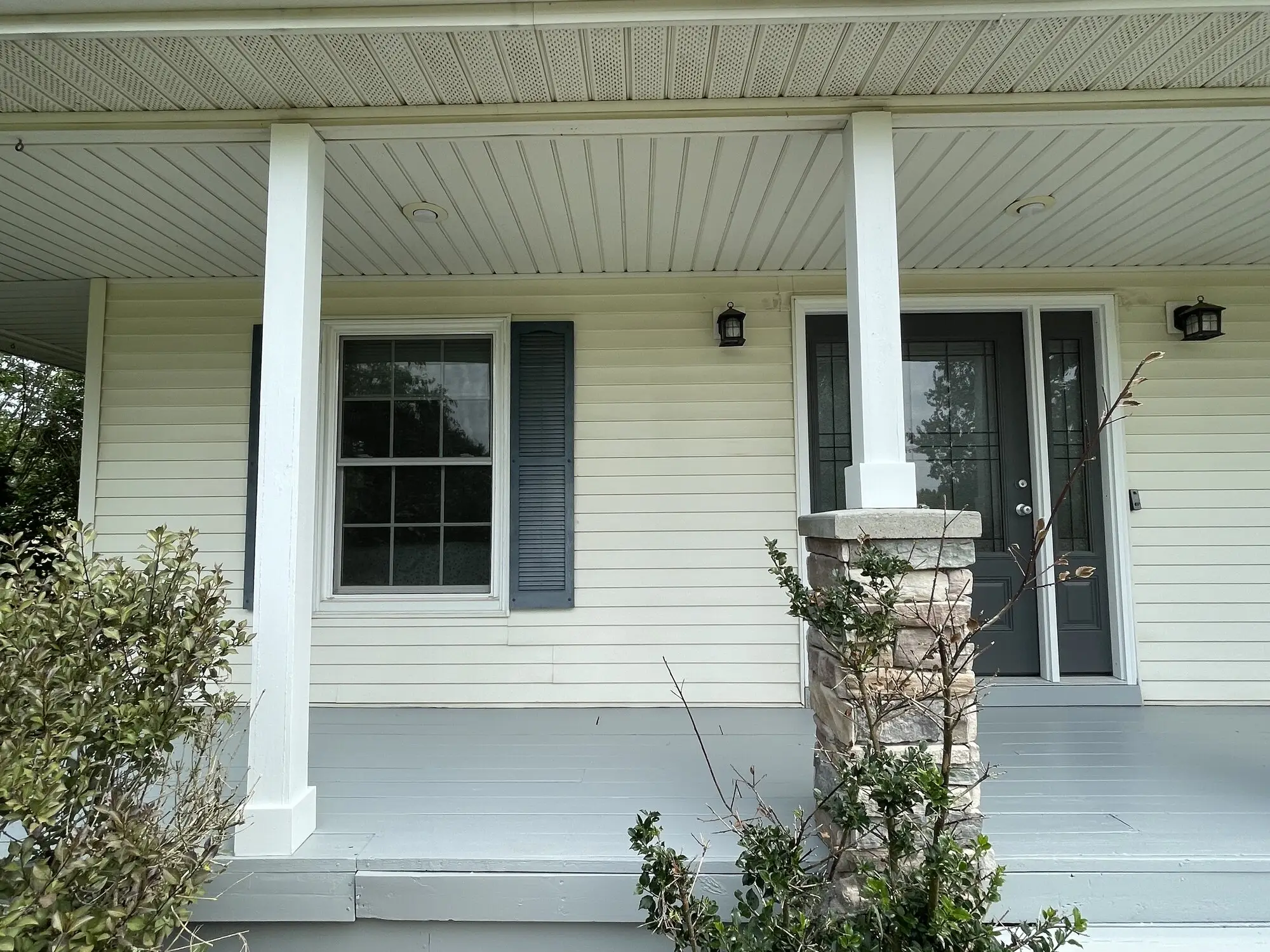 Covered porch with white columns, a painted ceiling and blue shutters