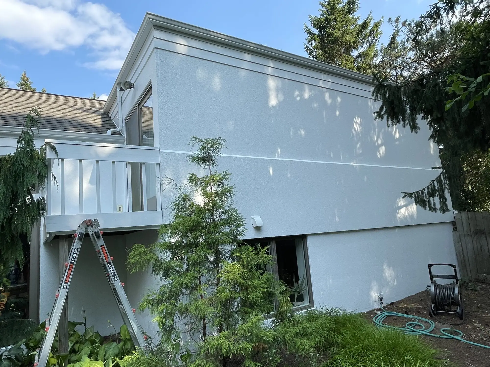 Two story white stucco home with a balcony rail after an exterior repaint